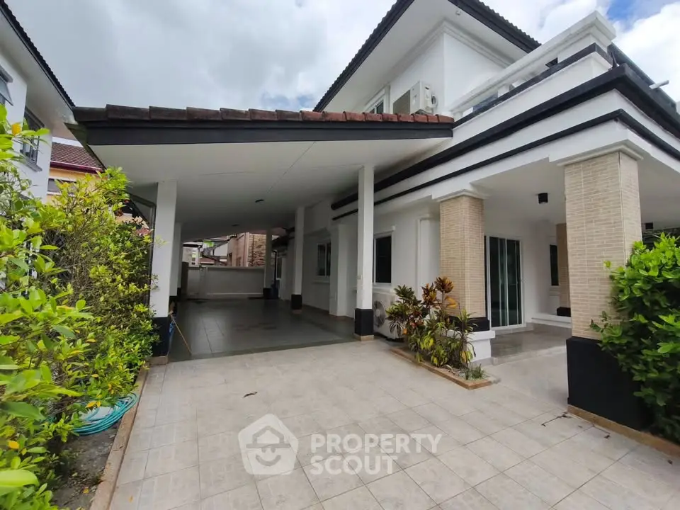 Spacious modern house exterior with covered carport and lush greenery, perfect for family living.