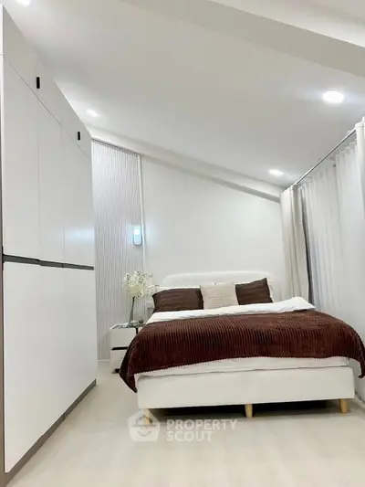 Modern bedroom with sleek white wardrobe and cozy bed, perfect for relaxation.