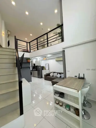 Modern loft-style living room with open kitchen and sleek staircase