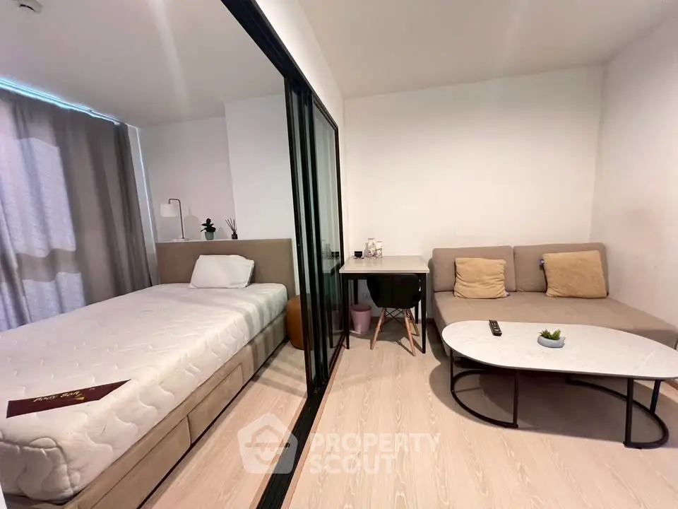 Modern studio apartment with cozy living area and comfortable bed, featuring sleek glass partition and stylish decor.