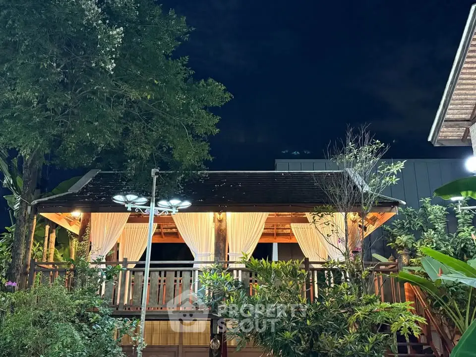 Charming outdoor gazebo with ambient lighting surrounded by lush greenery, perfect for relaxing evenings.