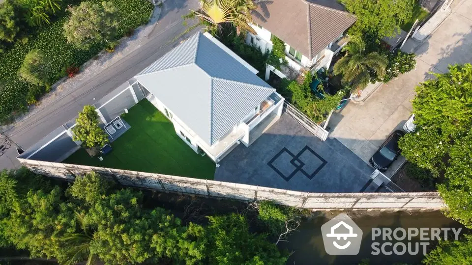 Aerial view of modern house with spacious driveway and lush greenery