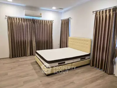 Spacious bedroom with elegant curtains and modern bed frame, perfect for comfort and style.