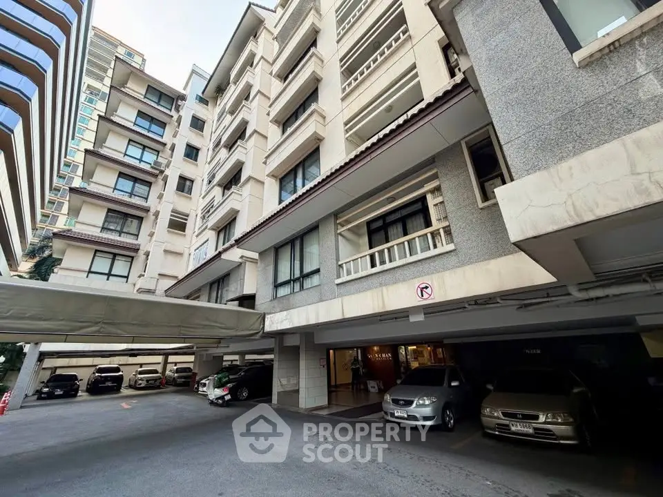 Modern apartment building with covered parking area and multiple floors.