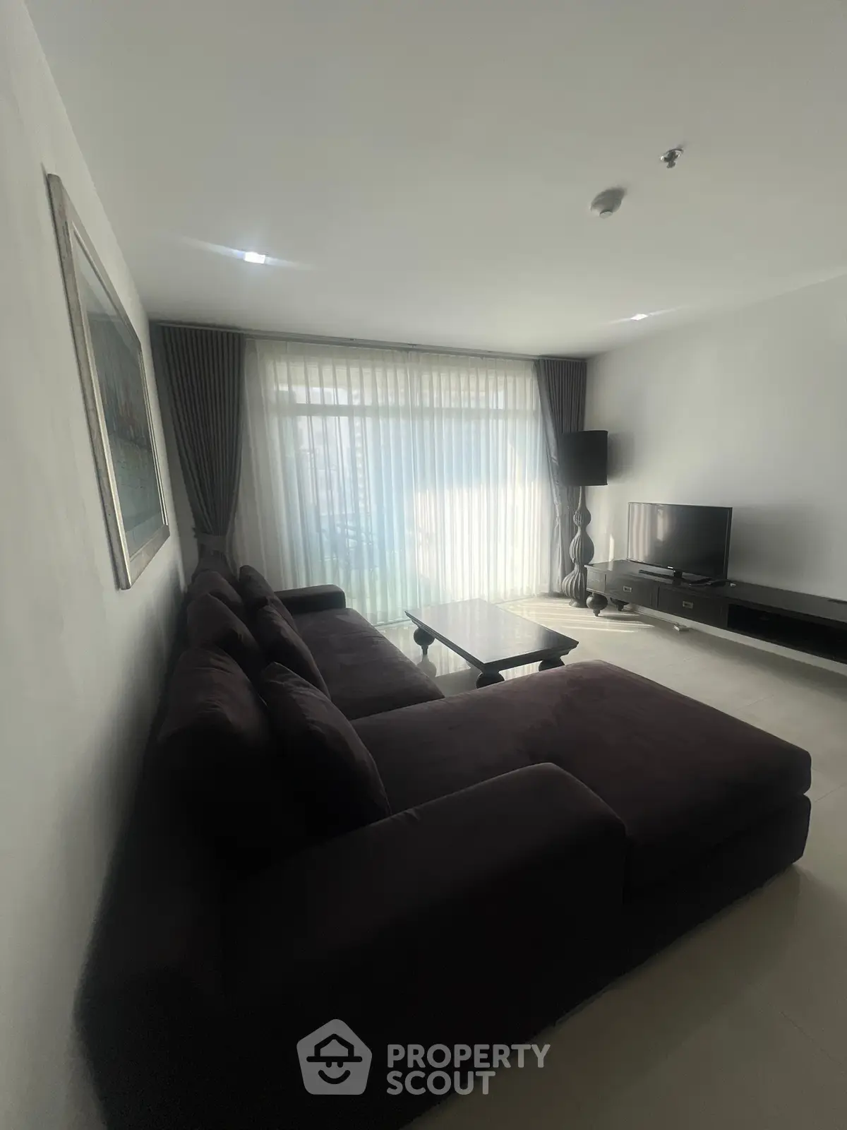Spacious living room with modern sofa and large window, perfect for relaxation.