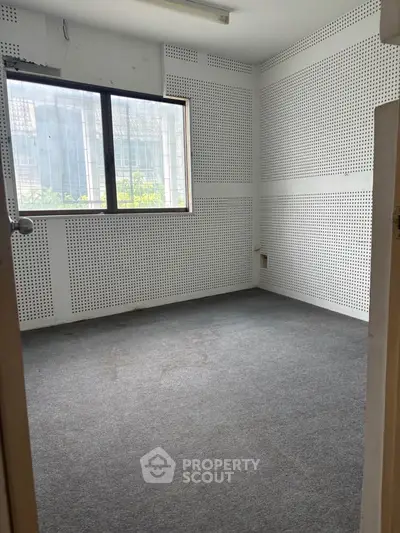 Spacious room with carpet flooring and large window in modern building.