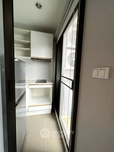 Compact modern kitchen with sleek white cabinets and large window for natural light.
