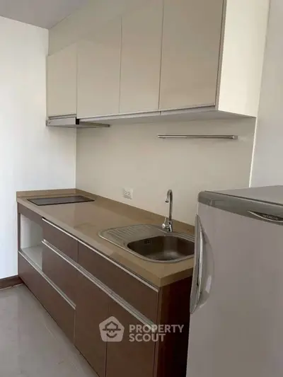 Modern kitchen with sleek cabinets and compact design, featuring a built-in stove and refrigerator.