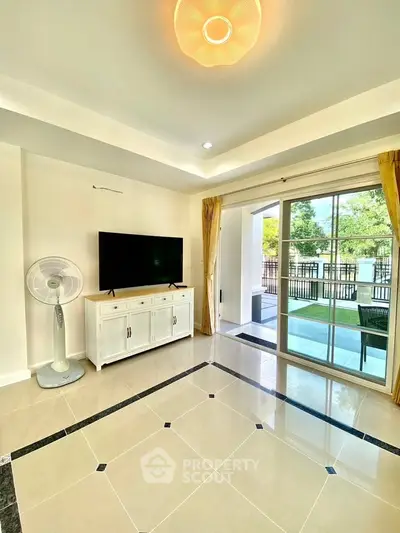 Bright living room with large windows and modern decor, opening to a spacious balcony with garden view.