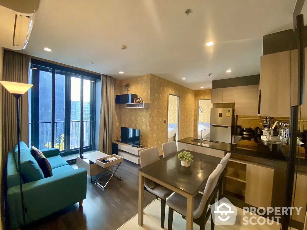 Elegant open-layout apartment with modern furniture, a cozy living area, and a fully equipped kitchen leading to a sunlit balcony.