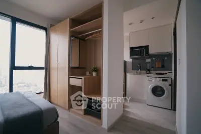Modern apartment with open kitchen and built-in wardrobe, featuring a washing machine and city view.