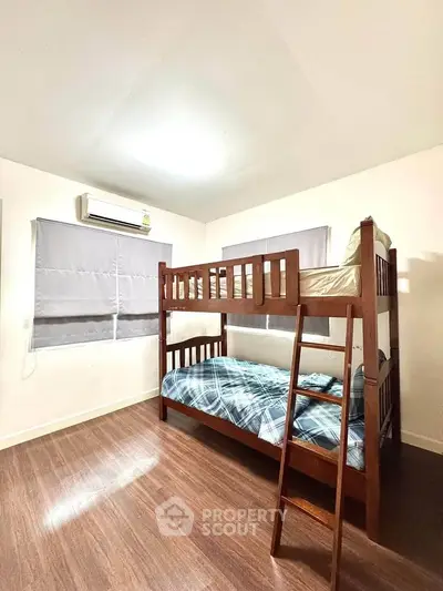 Cozy bedroom with wooden bunk beds and air conditioning, perfect for small spaces.