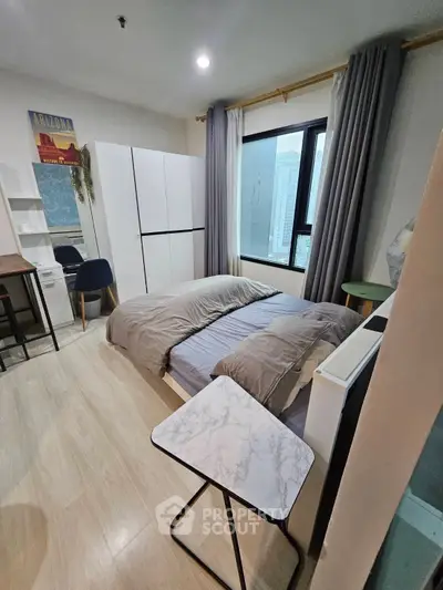 Modern bedroom with city view, featuring stylish decor and ample natural light.