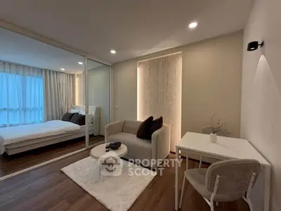 Modern living room with cozy seating and view into elegant bedroom