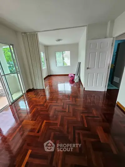 Spacious living room with polished wooden floors and large windows in a modern apartment.