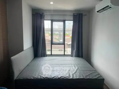 Cozy bedroom with large window and air conditioning, offering a serene view of the cityscape.