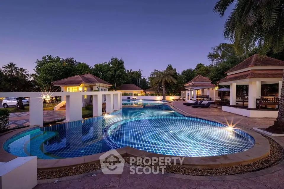 Luxurious resort-style pool with elegant cabanas and lush greenery at twilight.