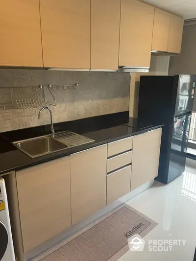 Modern kitchen with sleek cabinetry and black countertops in a stylish apartment.