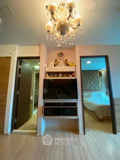 Elegant bedroom with chandelier and modern decor, featuring a cozy bed and stylish shelving.