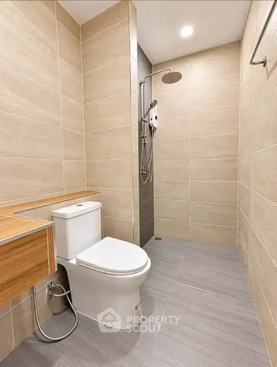 Modern bathroom with sleek fixtures and neutral tiles, featuring a shower and toilet.