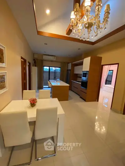 Luxurious open-layout kitchen with elegant chandelier and modern appliances, perfect for entertaining.