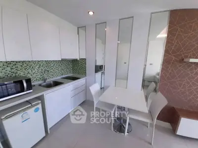 Modern kitchen with sleek white cabinets and mosaic backsplash in a stylish apartment.
