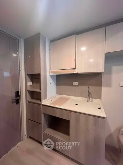 Modern compact kitchen with sleek cabinetry and integrated appliances in a stylish apartment.