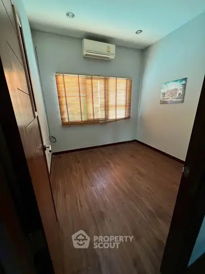 Cozy empty room with wooden flooring and air conditioning, perfect for customization.