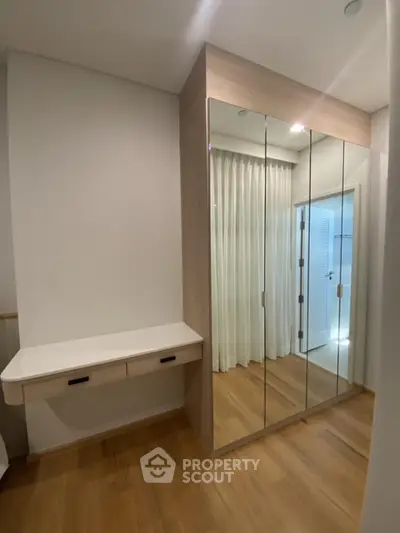 Modern bedroom with mirrored wardrobe and wooden flooring