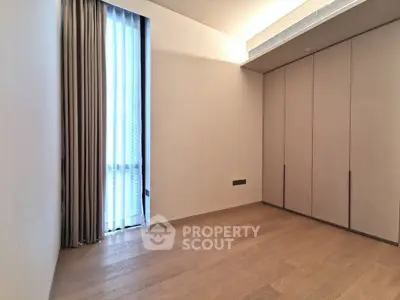 Spacious empty room with wooden flooring and large window, perfect for customization.