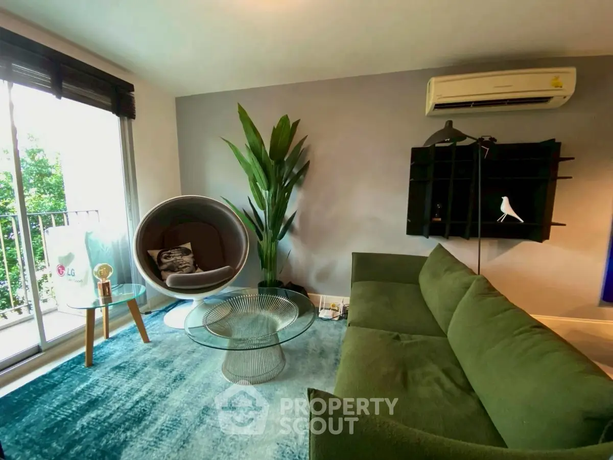 Modern living room with green sofa, unique chair, and large window view.