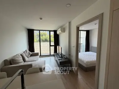 Modern apartment living room with cozy sofa and bedroom view