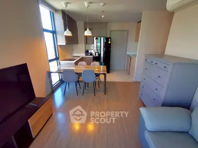 Modern open-plan living room with dining area and kitchen in stylish apartment.