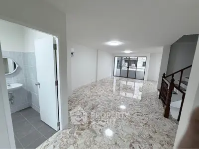 Spacious open-plan living area with marble flooring and large windows for natural light.