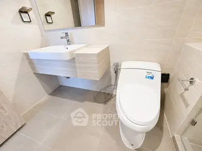 Modern bathroom with sleek fixtures and neutral tiles, featuring a floating sink and contemporary toilet design.