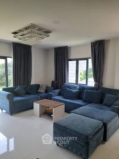 Spacious living room with elegant blue sofas and modern chandelier