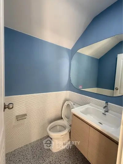Modern bathroom with blue walls, sleek vanity, and large mirror.