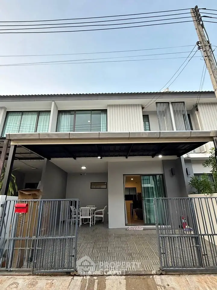 Modern townhouse exterior with gated entrance and covered parking area.