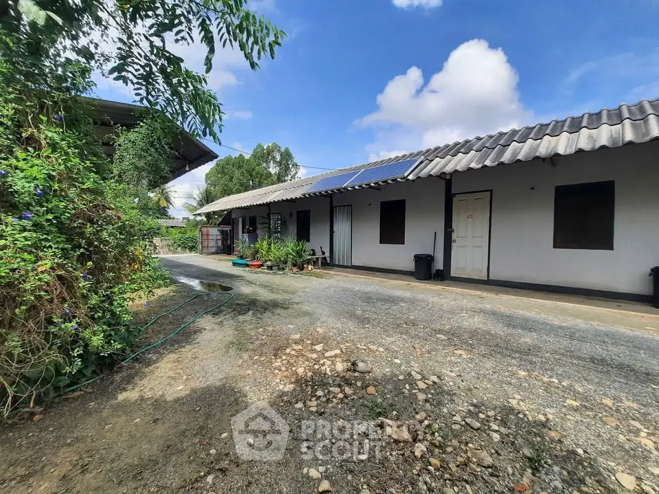Charming rural property with solar panels and lush greenery, perfect for sustainable living.