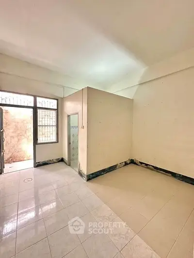Spacious unfurnished room with tiled flooring and natural light, ideal for customization.