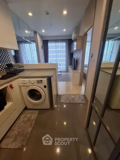 Modern apartment with open kitchen and living room, featuring a washing machine and stylish decor.