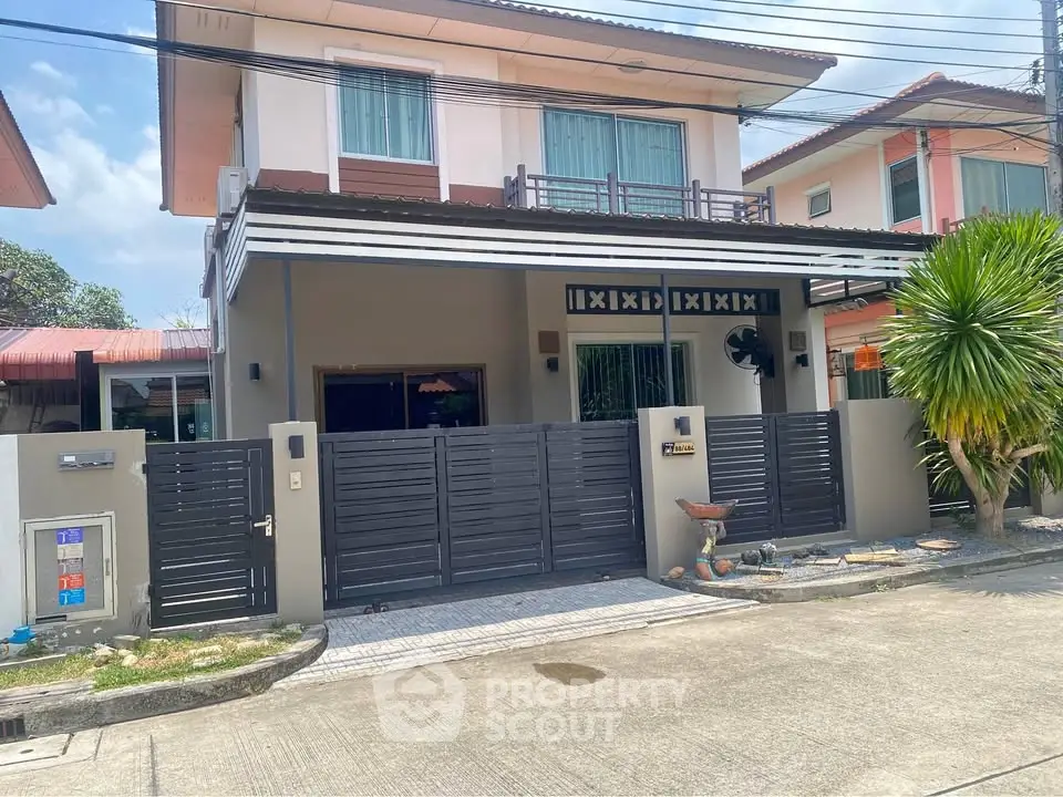Modern two-story house with gated entrance and balcony in a suburban neighborhood.