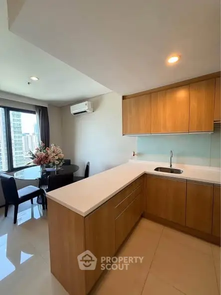 Modern kitchen with wooden cabinets and dining area in a high-rise apartment with city view.