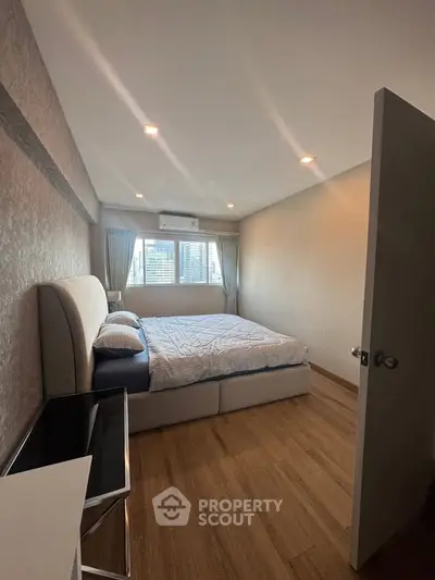 Spacious bedroom with modern decor and large window offering city views.