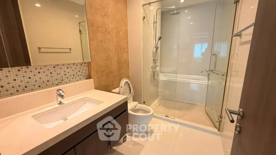 Modern bathroom with glass shower and elegant vanity in upscale apartment.