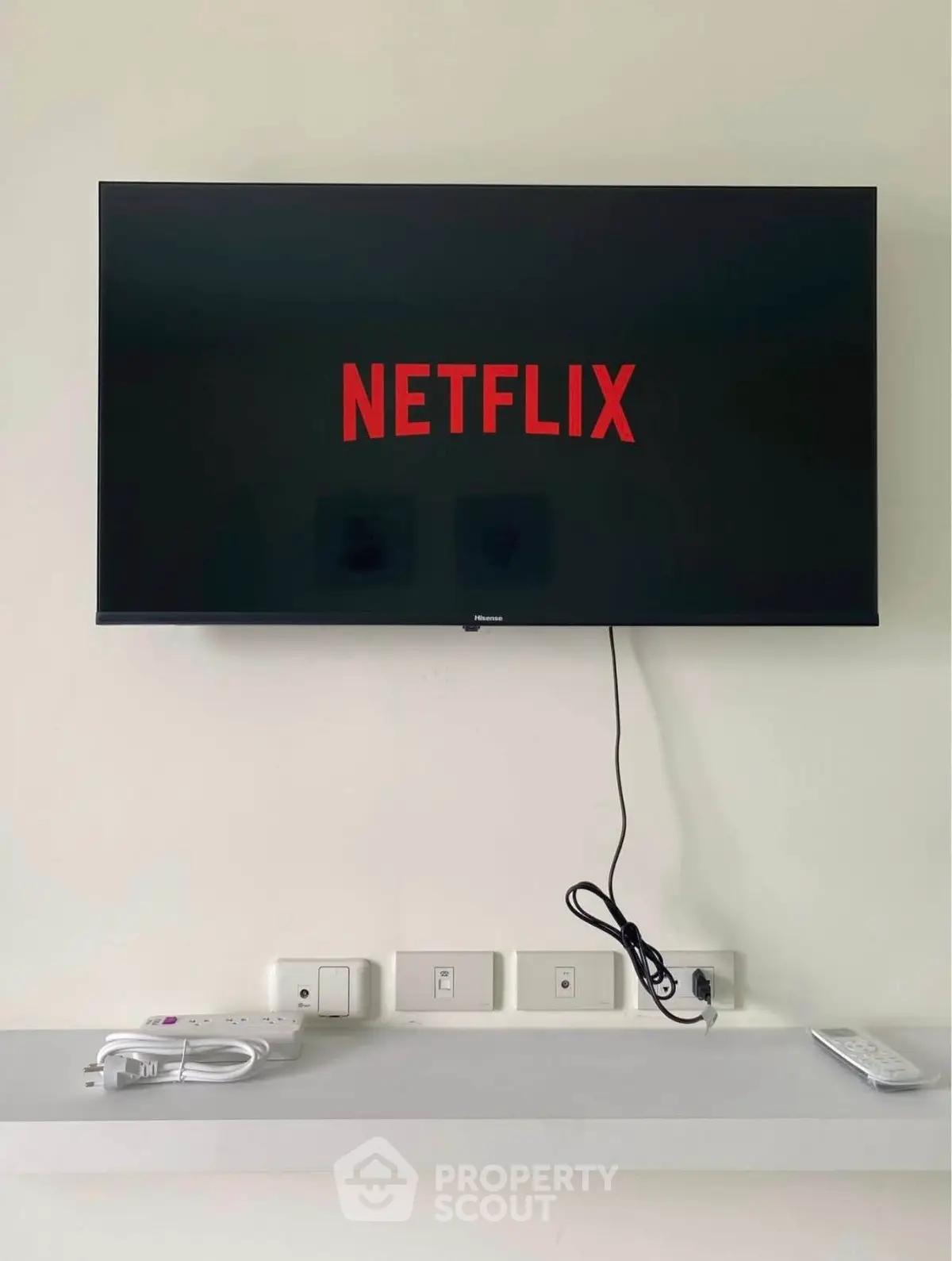 Modern living room with wall-mounted TV and Netflix on screen, showcasing sleek design.