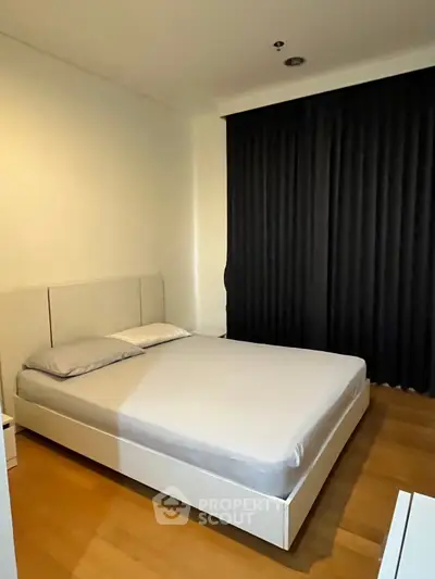 Modern bedroom with minimalist design and cozy ambiance, featuring a comfortable bed and sleek wooden flooring.