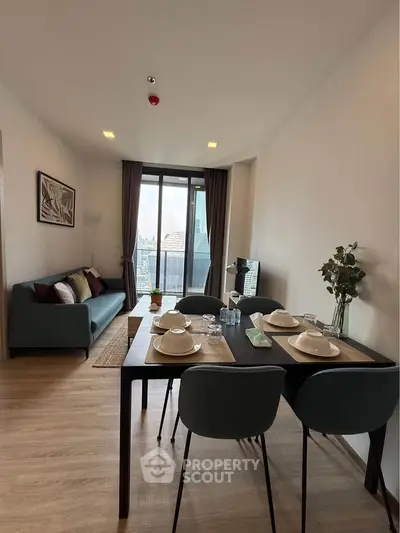 Modern living room with dining area and city view, featuring stylish decor and natural light.