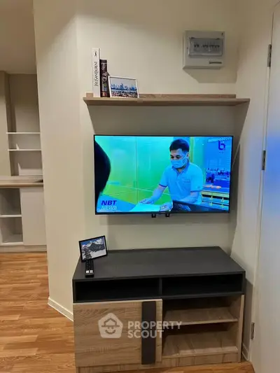 Modern living room with mounted TV and stylish wooden shelves, perfect for cozy evenings.