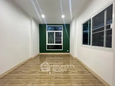 Spacious modern room with large window and stylish flooring, perfect for versatile living space.